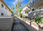 Thumbnail 24 of 51 - A sunny day in a residential area with apartment buildings and a sidewalk.