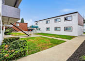 Thumbnail 50 of 55 - A white building with a brown roof is surrounded by a green lawn and a sidewalk.