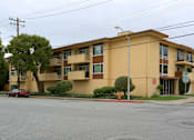 Thumbnail 6 of 32 - an apartment building on a street corner with a red car