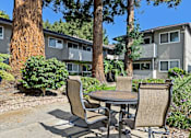 Thumbnail 7 of 37 - A patio with a table and chairs is surrounded by trees and houses.