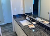 Thumbnail 15 of 43 - A bathroom with a granite counter top and a white vanity.