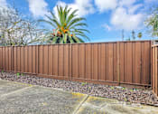 Thumbnail 15 of 38 - A brown fence with a palm tree in the background.