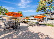 Thumbnail 24 of 40 - A patio with orange umbrellas and chairs.