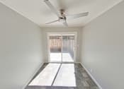 Thumbnail 33 of 47 - A room with a ceiling fan and a door leading outside.