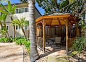 Thumbnail 2 of 37 - A wooden gazebo is surrounded by trees and plants.