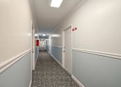 Thumbnail 9 of 16 - A long hallway with a red exit sign on the wall.