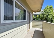 Thumbnail 12 of 32 - A balcony with a wooden floor and a window with a white frame.