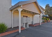 Thumbnail 6 of 35 - A building with a covered parking area in front.