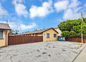 Thumbnail 4 of 38 - A house with a brown fence and a blue car in front.