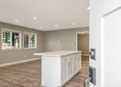 Thumbnail 53 of 62 - A white kitchen island with a countertop and cabinets in a room with a white door and window.