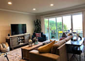 Thumbnail 9 of 22 - A living room with a brown couch, a wooden cabinet, and a flat screen TV.