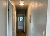 Thumbnail 21 of 22 - A long, narrow hallway with a carpeted floor and white walls.