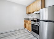 Thumbnail 28 of 29 - A kitchen with a stainless steel refrigerator, oven, and wooden cabinets.