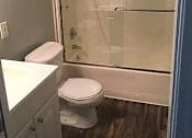 Thumbnail 29 of 31 - A white toilet sits in a bathroom next to a walk-in shower.