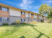 Thumbnail 21 of 40 - A row of apartment buildings with green lawns in front.