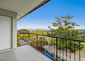 Thumbnail 6 of 10 - A balcony with a white door and a black railing overlooking a street.