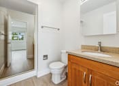 Thumbnail 9 of 10 - A bathroom with a toilet, sink, and mirror.