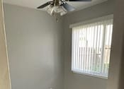 Thumbnail 27 of 33 - A room with a ceiling fan and a window with blinds.