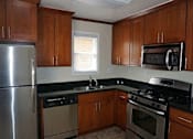 Thumbnail 12 of 22 - A kitchen with wooden cabinets and stainless steel appliances.
