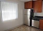 Thumbnail 11 of 22 - A kitchen with a stainless steel refrigerator and a window with blinds.