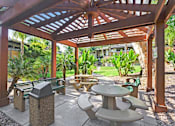 Thumbnail 26 of 38 - A wooden pergola with a table and chairs underneath it.
