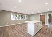 Thumbnail 60 of 62 - A kitchen with a white island and wooden floors.