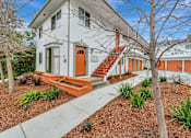 Thumbnail 19 of 29 - A white house with a red door and orange stairs.