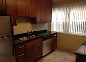 Thumbnail 20 of 22 - A kitchen with wooden cabinets and a black countertop.
