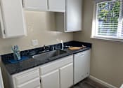 Thumbnail 7 of 43 - A kitchen with white cabinets and a black countertop.