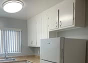 Thumbnail 32 of 37 - A white refrigerator in a kitchen with wooden floors and white cabinets.