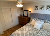 Thumbnail 25 of 32 - a bedroom with a bed and a dresser and a ceiling fan