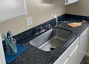 Thumbnail 37 of 43 - A kitchen with a granite countertop and white cabinets.