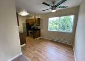 Thumbnail 48 of 51 - an empty living room with a kitchen and a ceiling fan