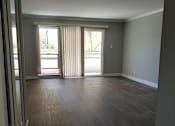 Thumbnail 24 of 30 - A room with a wooden floor and a sliding glass door.