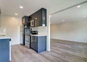 Thumbnail 57 of 62 - an empty living room with a kitchen with a stove and refrigerator