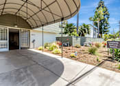 Thumbnail 37 of 43 - The image shows a leasing office with a curved roof and a garden in front.
