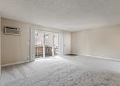 Thumbnail 39 of 51 - A room with a carpeted floor and a sliding glass door leading to a balcony.