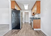 Thumbnail 26 of 52 - A kitchen with a black refrigerator and wooden cabinets.