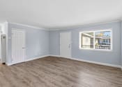 Thumbnail 6 of 17 - A room with light blue walls and wooden flooring with a window.