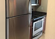 Thumbnail 18 of 22 - A stainless steel refrigerator with a black oven beneath it.