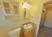 Thumbnail 16 of 22 - A bathroom with a sink, toilet, and mirror.