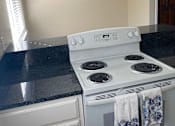 Thumbnail 11 of 43 - A white stove top oven with a blue and white towel hanging on it.