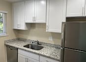Thumbnail 16 of 43 - A kitchen with white cabinets and a granite countertop.