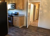 Thumbnail 19 of 22 - A kitchen with wooden cabinets and a black refrigerator.