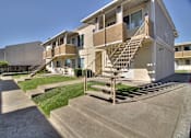 Thumbnail 5 of 33 - A concrete staircase leads to a balcony on a two-story apartment building.