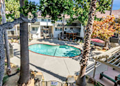 Thumbnail 9 of 43 - A pool surrounded by trees and a building in the background.