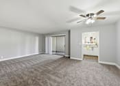 Thumbnail 7 of 33 - A room with a ceiling fan and carpeted floor.