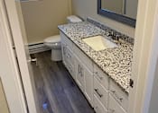 Thumbnail 17 of 43 - A bathroom with a granite counter top and white cabinets.