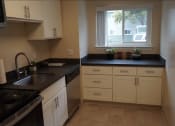 Thumbnail 3 of 22 - a kitchen with black counters and white cabinets and a window