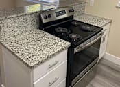Thumbnail 24 of 43 - A kitchen with granite countertops and white cabinets.